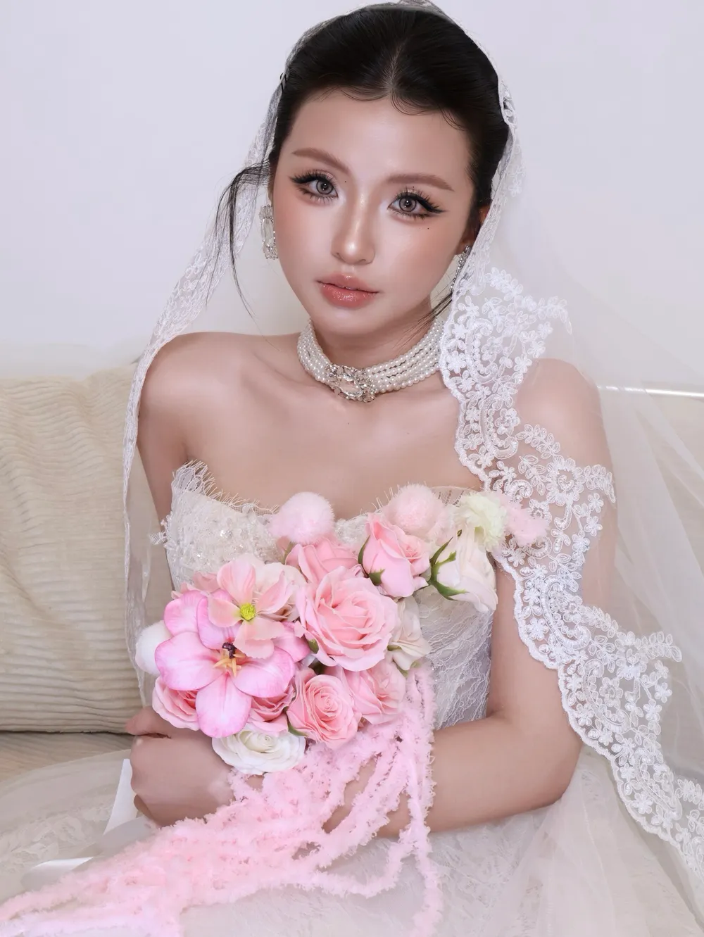 Cô dâu nhìn thẳng ống kính, mắt trang điểm nâu khói nhẹ, môi nude hồng
