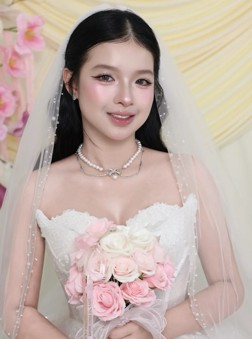 Cô dâu cười tươi, voan tulle phủ vai, ôm bó hồng phấn trước ngực