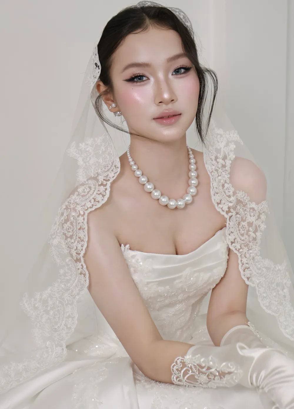 Cô dâu trong váy satin và găng tay lụa dài, voan ren phủ vai, tóc búi thấp