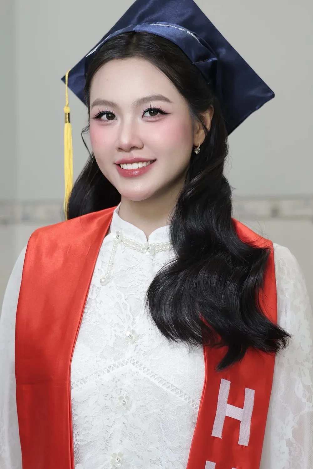 Nữ sinh trang điểm tốt nghiệp rạng rỡ trong áo dài trắng và cử nhân đỏ